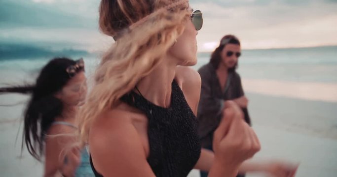 Hipster Girl Dancing on Beach with friends at seaside