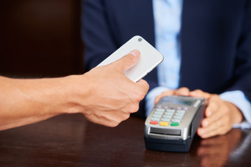 Gast bezahlt Hotel Rechnung mit Smartphone