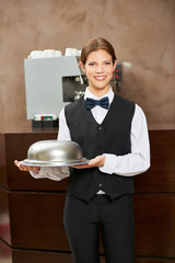 Kellnerin in Uniform mit Speiseglocke