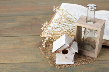 birdhouse with a twig on the burlap with decorative branches and glass vase on burlap on wooden background