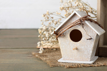 birdhouse with a twig on the burlap with decorative twigs on burlap on wooden background