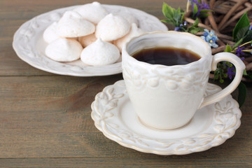 a Cup of coffee with cookies on the plate and the wreath of twigs on wooden background