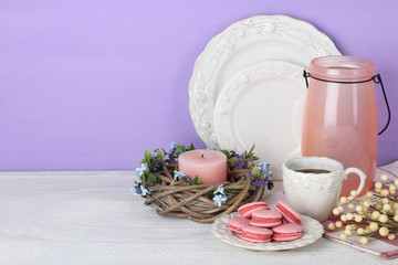 macaroon with a Cup of coffee near the wreath and a vase with decorative twigs on wooden background
