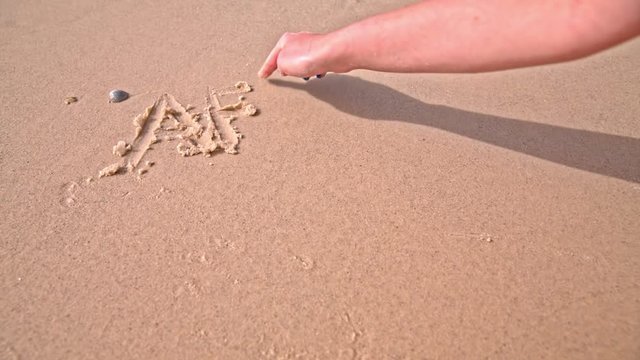 Hand writes AFRICA in to beach sand