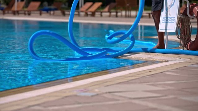 Person cleaning pool with special blue tubes