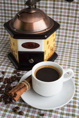 Cup of coffee and coffee mill on a light background with cinnamon. 