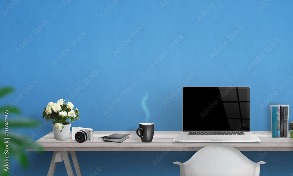Wall mural laptop with blank screen on office desk. free space on wall for text. blue wall in background.