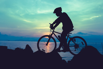 Healthy lifestyle. Silhouette of bicyclist riding the bike at seaside.