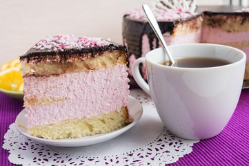 Biscuit cake with fruit souffle, decorated with chocolate and cup of tea. Piece of Cake is insulated.