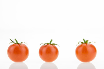 Three cherry tomatoes with reflections, on white background with copy-space