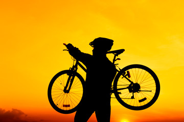 Fototapeta na wymiar Healthy lifestyle. Silhouette of bicyclist carrying his bicycle