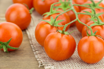 Heap of cherry tomatoes, on wooden surface and cloth