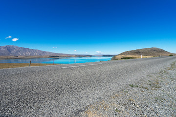 asphalt road near lake in summer day in new zealand