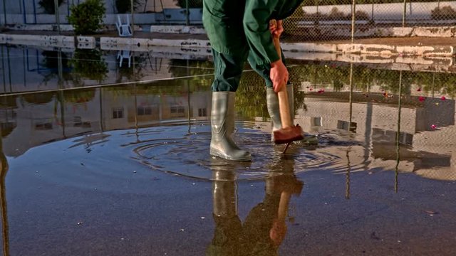 Man stand in puddle and hammer nail in ground