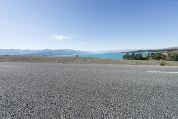 asphalt road near lake in summer day in new zealand