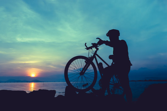 Healthy lifestyle. Silhouette of bicyclist standing with bike at seaside