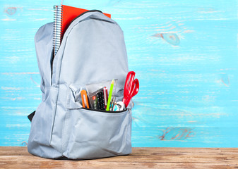 Backpack with school tools on turquoise background