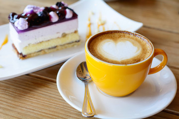 hot coffee latte art and coffee foam with Blueberry Cake on wood