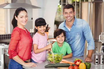 Portrait of happy family preparing salad
