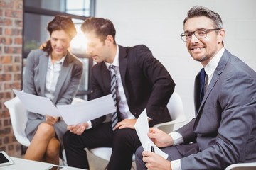 Fototapeta premium Portrait of smiling businessman with coworkers discussing