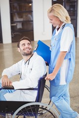 Obraz premium Smiling doctor on wheelchair interacting with female colleague 