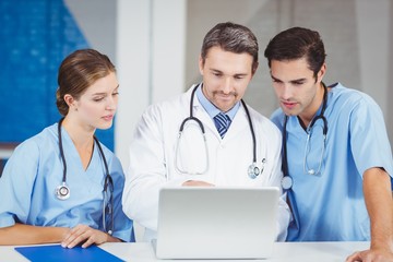 Concentrated doctors using laptop while standing at desk 