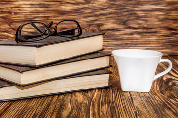 Glasses with books and cup of coffee on the table