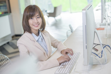 Attractive asian business woman working on computer in workplace