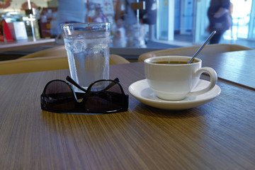 Coffee, glass of water and sunglasses on table