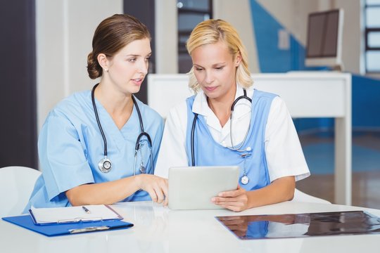 Female doctors using digital tablet while sitting at desk 
