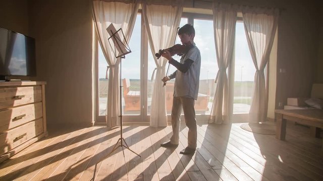 Playing violin in beautiful home room with sun shining