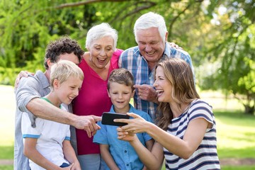 Fototapeta premium Smiling family using smartphone