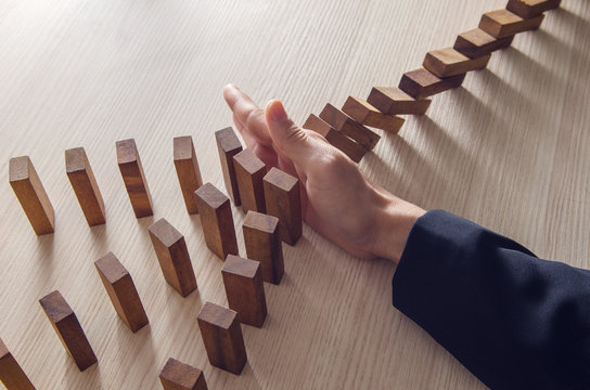 Businesswoman hand stopping the domino wooden effect concept for business.