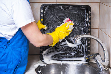 Female janitor with sponge cleaning dirty pan