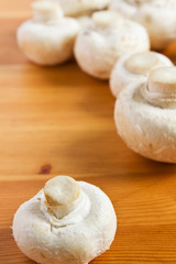 White raw champignon closeup lie on a wooden table.