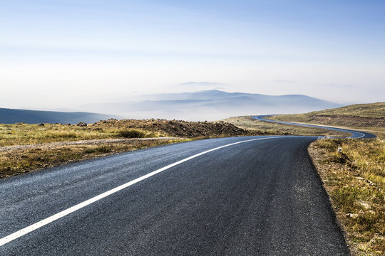 Scenic view of road against sky in grassy landscape