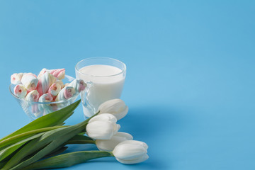 Obraz na płótnie Canvas Milk amd flowers on blue background