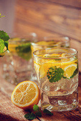 Fresh lemon drink with sugar and mint on wooden background
