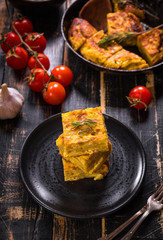 Slice of tortilla de patatas on a black plate