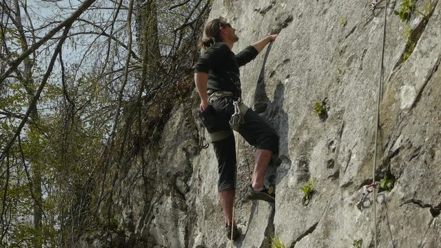 Male rock climber taking a climbing chalk dust, climb and secure with carabiner and rope. Low angle view.
