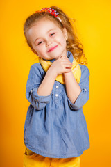 Funny little girl on a bright yellow background.