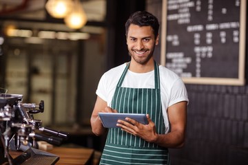 Smiling barista using tablet and looking at the camera - obrazy, fototapety, plakaty