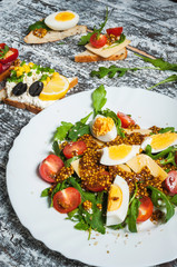 Salad and variety of open sandwiches with different toppings on white background