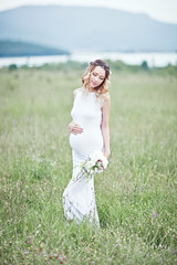 Fototapeta na wymiar Pregnant woman enjoying summer park, wearing long white dress