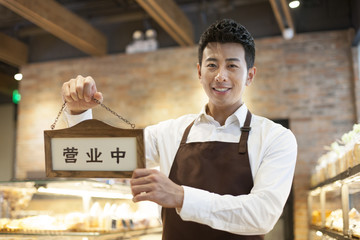 Young man holding an open sign
