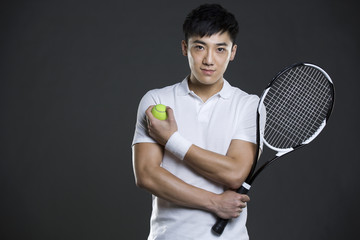 Young man holding tennis ball and racket