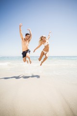 Happy couple jumping on the beach