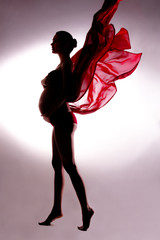 Body contour of pregnant woman in flying tissues in studio with vignettes background
