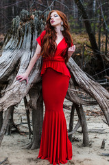 Beautiful girl in a red dress on a sandy beach