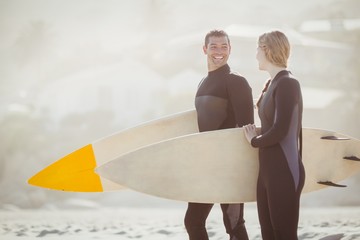 Couple with surfboard standing on the beach